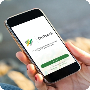 A hand holds a cell phone with the OnTrack app open on screen.